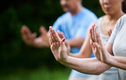 People practicing Tai Chi holding their hands up