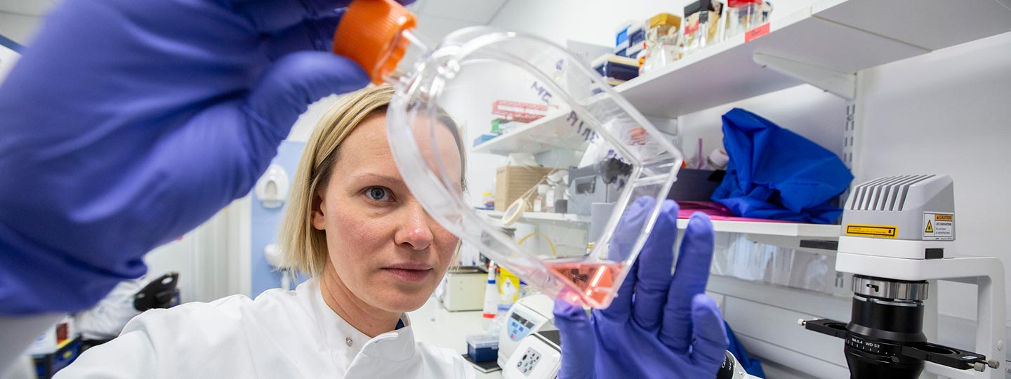 Research looking at a bottle with pink liquid in it.