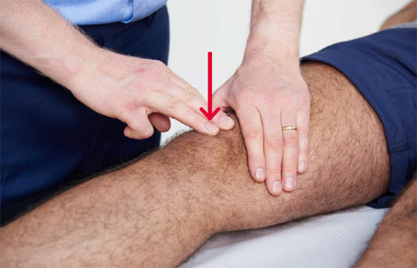A doctor examining a knee joint.
