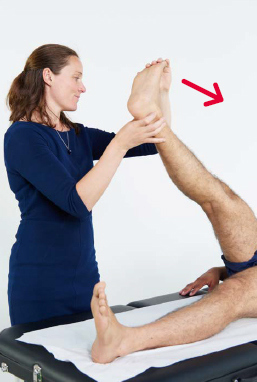A healthcare professional lifting the leg of a man who is laid down.