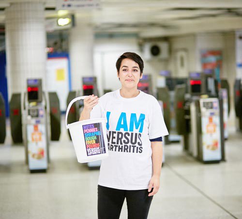 A Versus Arthritis staff member holding a collection bucket.