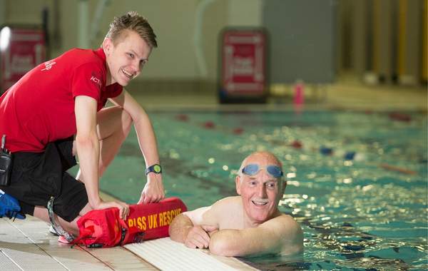 Man swimming in pool talking to lifeguard