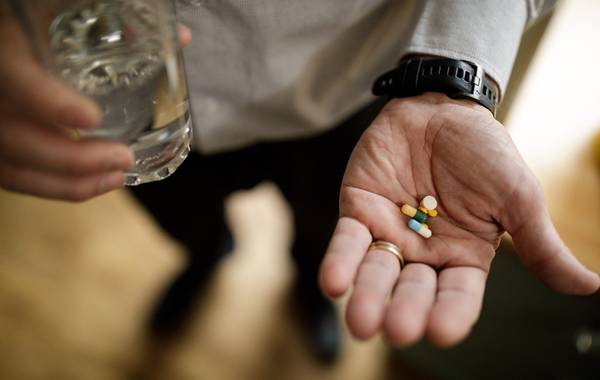 Tablets and glass if water in a person's hands