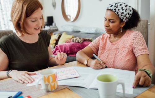 Two woman talking writing notes