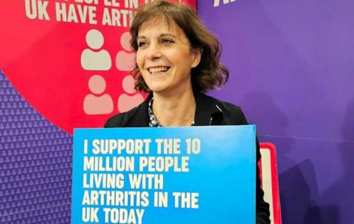 Deborah Alsina, Chief Executive of Versus Arthritis, holding a sign which reads: "I support the 10mn people living with arthritis in the UK today"