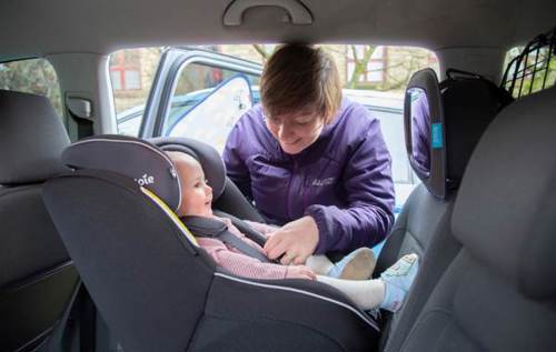 Woman clipping baby into car seat