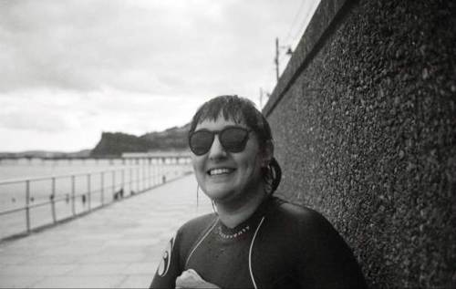 Women on boardwalk in a wetsuit wearing sunglasses