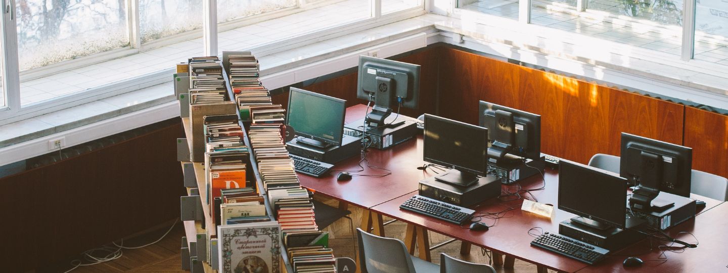 University library consisting of shelves with books and computers on desk tables