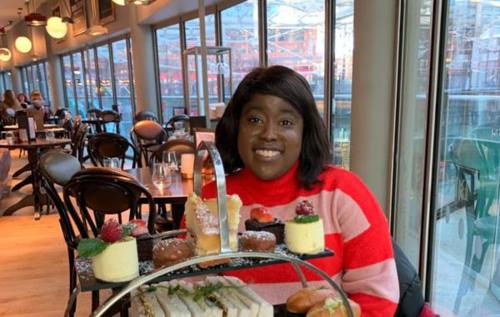 Smiling Melissa sitting behind a restaurant table which has an afternoon tea on top