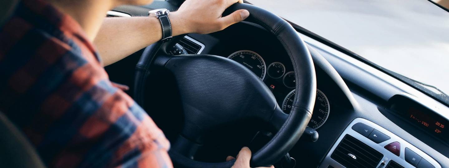 Person holding steering wheel