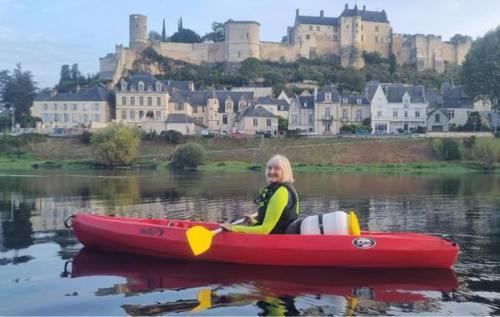 Smiling Josephine in red kayak on a river beside a castle